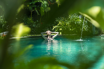 Image showing Sensual young woman relaxing in outdoor spa infinity swimming pool surrounded with lush tropical greenery of Ubud, Bali.