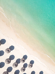 Image showing Aerial view of amazing tropical white sandy beach with palm leaves umbrellas and turquoise sea.