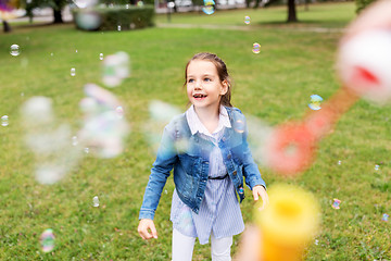 Image showing happy girl playing with soap bubbles at park