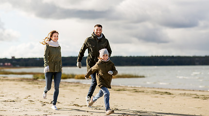 Image showing happy family running along autumn beach