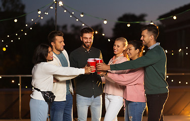 Image showing friends clinking party cups on rooftop at night