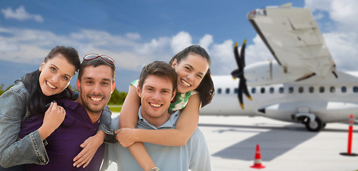 Image showing happy friends over plane on airfield background