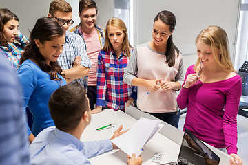 Image showing students and teacher with papers and laptop