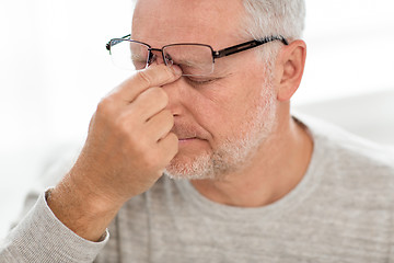 Image showing senior man in glasses massaging nose bridge