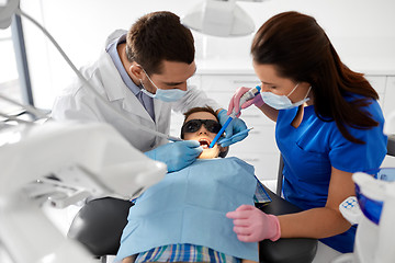 Image showing dentist treating kid teeth at dental clinic