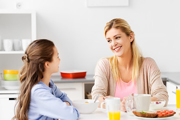 Image showing happy mother and daughter having breakfast at home