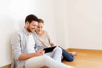 Image showing happy couple with tablet pc computer at new home