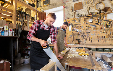 Image showing carpenters working with saw and wood at workshop