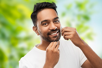 Image showing indian man with dental floss cleaning teeth