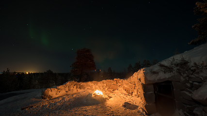 Image showing Warm light of the fire and polar lights in night sky