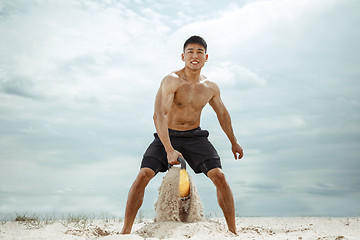 Image showing Young healthy man athlete doing squats at the beach