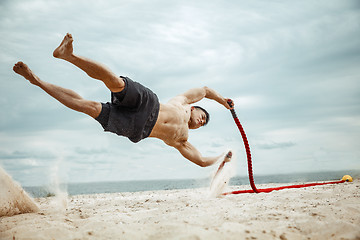 Image showing Young healthy man athlete doing squats at the beach