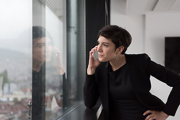 Image showing Elegant Woman Using Mobile Phone by window in office building