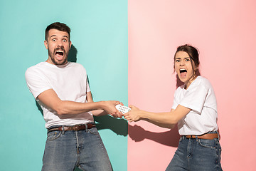 Image showing young couple watching tv and fighting to get the remote control