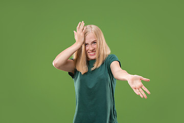 Image showing Beautiful female half-length portrait isolated on green studio backgroud. The young emotional surprised woman