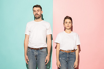 Image showing The serious man and woman looking at camera against pink and blue background.