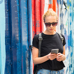 Image showing Woman using smartphone against colorful graffiti wall in New York city, USA.