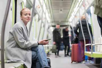 Image showing Beautiful blonde woman using smart phone while traveling by metro public transport.