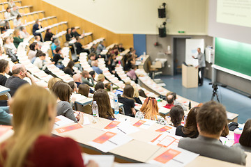 Image showing Audience in the lecture hall. Female student making notes.