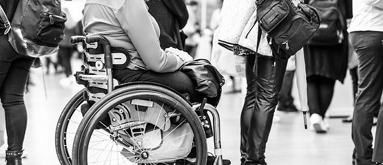 Image showing Close up of unrecognizable hanicapped woman on a wheelchair queuing in line to perform everyday tasks.