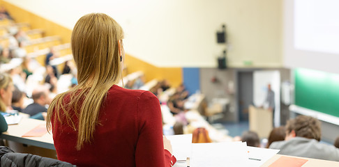 Image showing Female student attending faculty lecture workshop making notes.