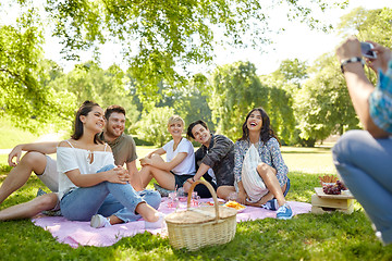 Image showing man photographing friends by smartphone at picnic