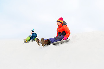 Image showing happy kids sliding on sleds down hill in winter