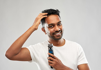 Image showing smiling indian man with trimmer touching his hair