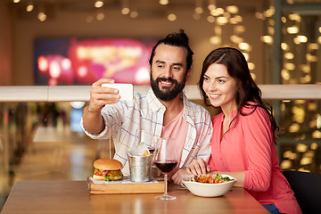 Image showing couple taking selfie by smartphone at restaurant