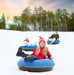 Image showing happy friends sliding down hill on snow tubes