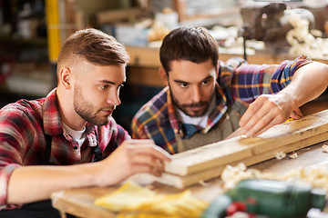 Image showing carpenters measuring wooden board at workshop