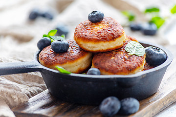 Image showing Cheese pancakes and blueberries in cast iron pan.