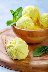 Image showing Golden colored turmeric ice cream in wooden bowl.