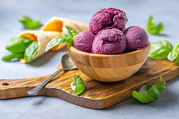 Image showing Blueberry ice cream balls and green basil in a wooden bowl.