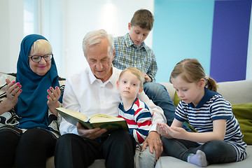 Image showing modern muslim grandparents with grandchildren reading Quran