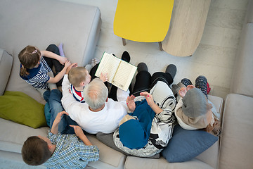 Image showing top view of modern muslim grandparents with grandchildren readin