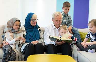 Image showing modern muslim grandparents with grandchildren reading Quran