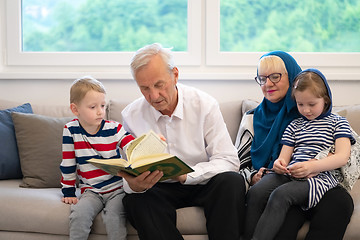 Image showing modern muslim grandparents with grandchildren reading Quran