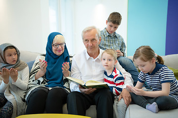 Image showing modern muslim grandparents with grandchildren reading Quran