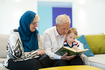 Image showing modern muslim grandparents with grandchildren reading Quran