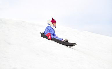 Image showing happy little girl sliding down on sled in winter