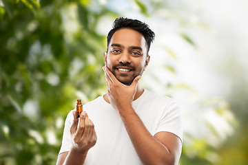 Image showing indian man applying natural grooming oil to beard