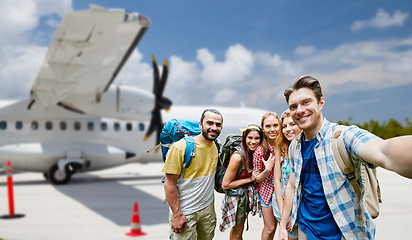 Image showing friends taking selfie over plane on airfield