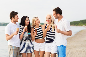 Image showing happy friends eating ice cream on beach