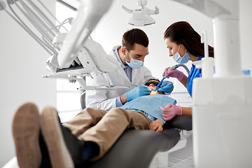 Image showing dentist treating kid teeth at dental clinic