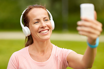 Image showing woman in phones takes selfie by smartphone at park