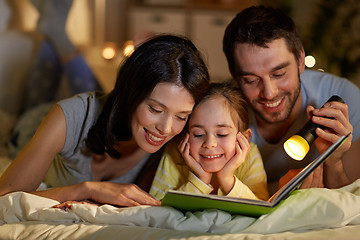 Image showing happy family reading book in bed at night at home