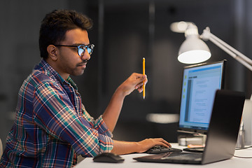 Image showing creative man working with laptop at night office