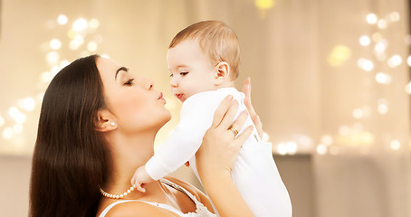 Image showing mother kissing baby over christmas lights