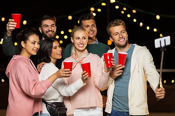 Image showing friends with drinks taking selfie at rooftop party